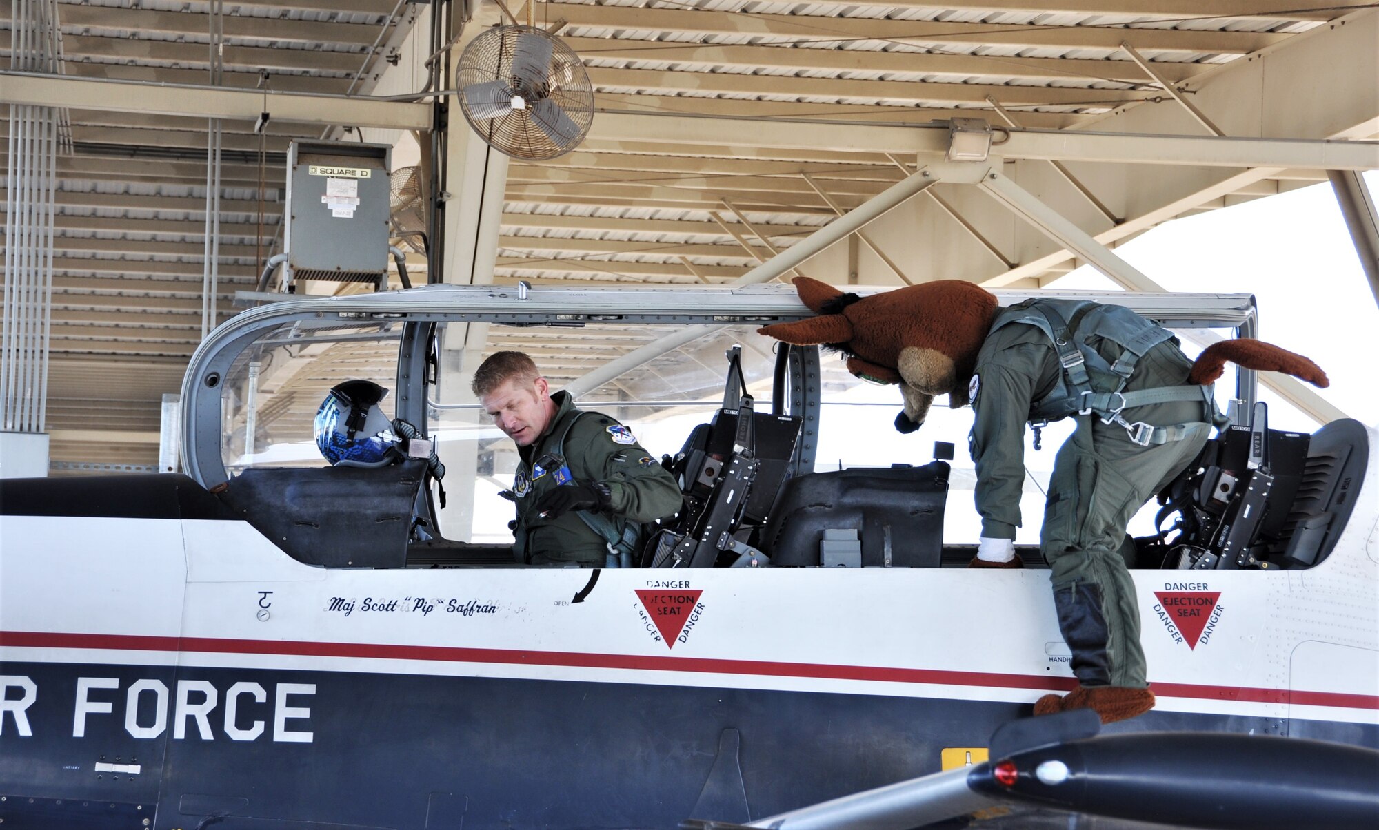 The Spurs Coyote boards the aircraft for his simulated flight with his friend from the 340th Flying
 – Lt. Col. Mark Pasierb – at Joint Base San Antonio-Randolph, Texas February 25 where Regular Air Force, Air Force Reserve, and civilian Airmen from the 340th Flying Training Group headquarters, 39th Flying Training Squadron T-6 Texan Flight, 12th Flying Training Wing Safety, 559th Flying Training Squadron T-6 team, and 3rd Combat Camera Squadron (JBSA-Lackland) members, and the NBA San Antonio Spurs production crew worked to put the Coyote through the pilot training process. Video footage will be used for a Spurs Military Appreciation video to be shown during the March 10 game.  (U.S. Air Force photo by Janis El Shabazz)