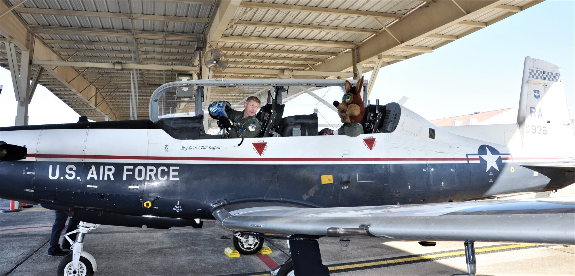The Spurs Coyote gets last minute instructions for his simulated flight  from his friend 340th Flying Training Group’s – Lt. Col. Mark Pasierb – at Joint Base San Antonio-Randolph, Texas February 25 where Regular Air Force, Air Force Reserve, and civilian Airmen from the 340th Flying Training Group headquarters, 39th Flying Training Squadron T-6 Texan Flight, 12th Flying Training Wing Safety, 559th Flying Training Squadron T-6 team, and 3rd Combat Camera Squadron (JBSA-Lackland) members, and the NBA San Antonio Spurs production crew worked to put the Coyote through the pilot training process. Video footage will be used for a Spurs Military Appreciation video to be shown during the March 10 game.  (U.S. Air Force photo by Janis El Shabazz)