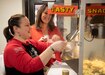 Lori Rozhon, Soldier Family Readiness Group (SFRG) leader for the 1st Theater Sustainment Command (TSC), scoops popcorn into a bag for a weekly fundraiser Feb. 27, 2020 at Fowler Hall, Fort Knox, Ky., as Theresa Scott, family readiness support assistant, 1st TSC looks on. The SFRG sells popcorn and other snacks to raise money for events for Soldiers, civilians and families of the 1TSC. (U.S. Army photo by Wendy Arevalo).