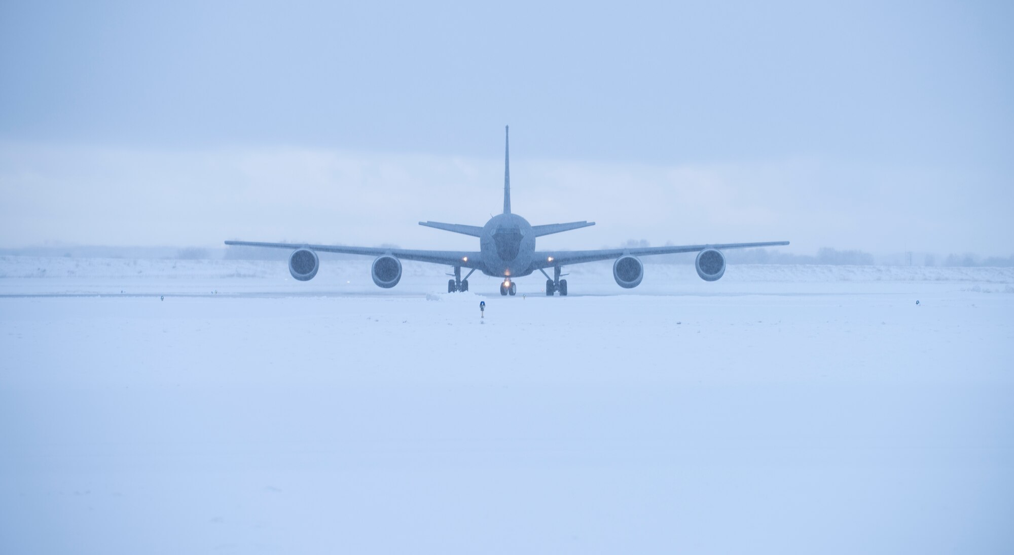 Military refueling taxis on snowy runway.