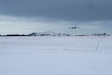 Military refueling aircraft preparing to land onto snowy runway.