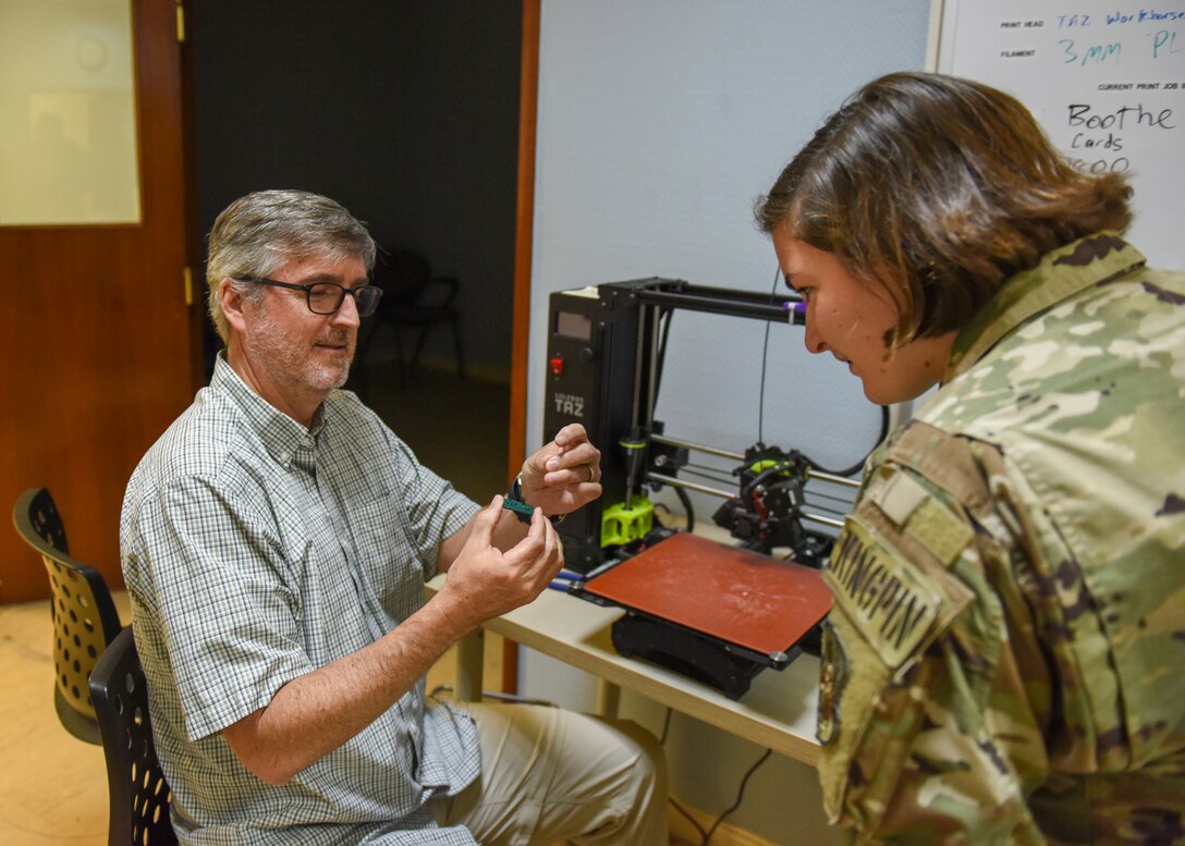 Doug Rider, a senior systems engineer contractor, shows U.S. Air Force Capt. Claire Hoover, an air battle manager assigned to the 727th Expeditionary Air Control Squadron, deployed to Al Dhafra Air Base, United Arab Emirates, a 3D printed game piece during the U.S. Air Forces Central Command Innovation Summit in the 379th Air Expeditionary Wing’s Desert Spark Lab at Al Udeid Air Base, Qatar, March 3, 2020.