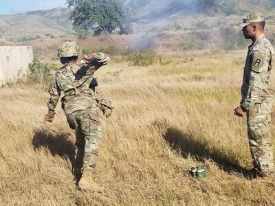 Staff Sgt. Barbara Guishard throws a pyrotechnic during an Observer Coach Trainer course at Camp Santiago, Puerto Rico in February 2020. The OC/T course instills professionals with the knowledge to properly validate each unit at the home station and deployment mobilization centers.