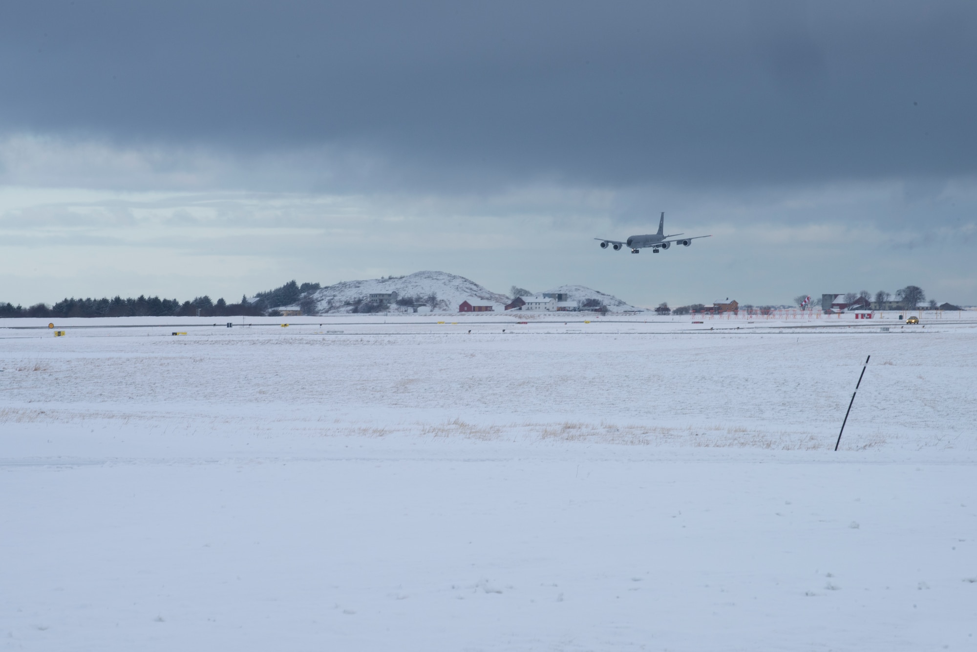 Military refueling aircraft preparing to land onto snowy runway.