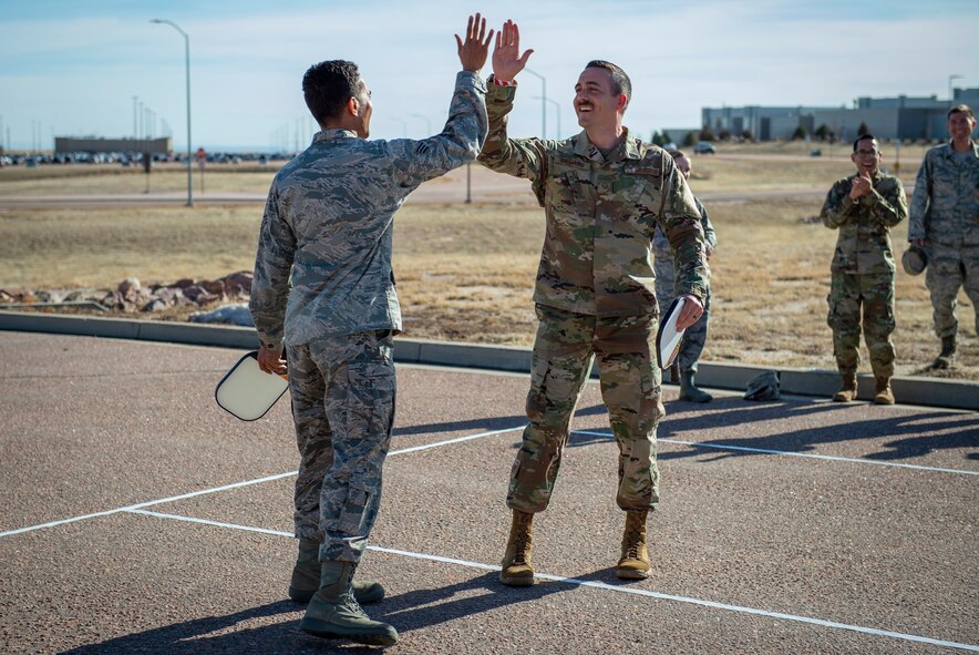 From left, Senior Airman Sean Musrasrik, 50th Comptroller Squadron financial operations technician, and Staff Sgt. Christopher Williams, 50th CPTS financial operations supervisor, high-five while playing Pickleball during First Friday at Schriever Air Force Base, Colorado, March 6, 2020. Team Schriever members are encouraged to participate in First Friday to build connections and strengthen resilience. (U.S. Air Force photo by Airman Amanda Lovelace)