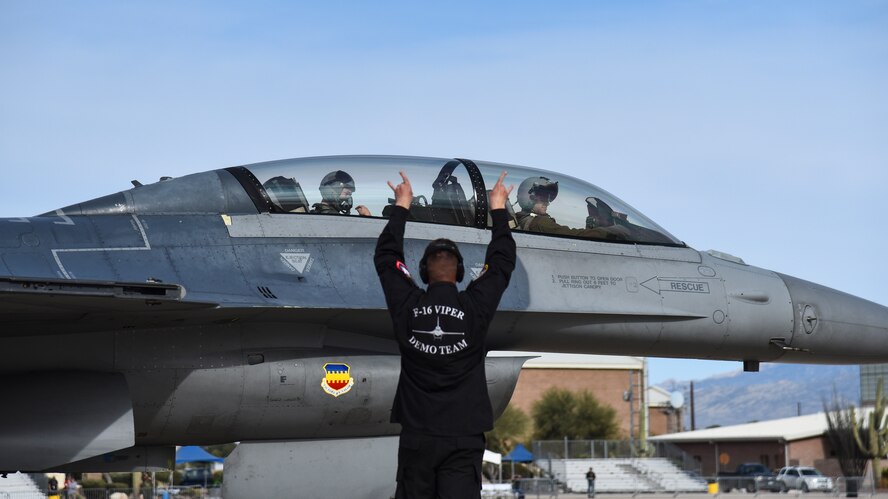 A photo of a crew chief signaling an F-16 to takeoff.