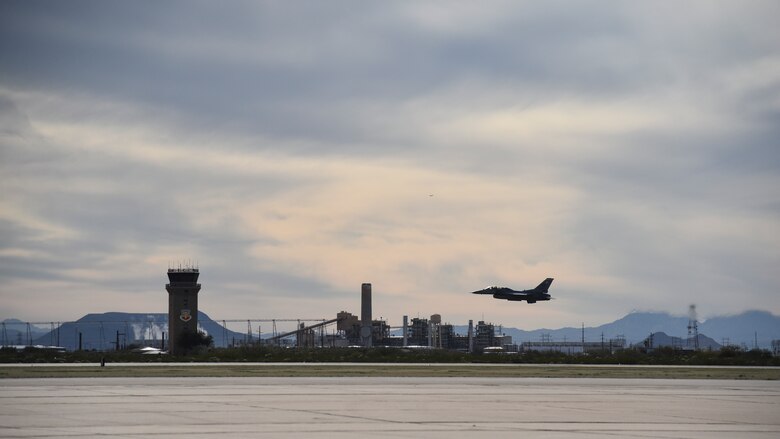 A photo of an F-16 taking off from a flight line.