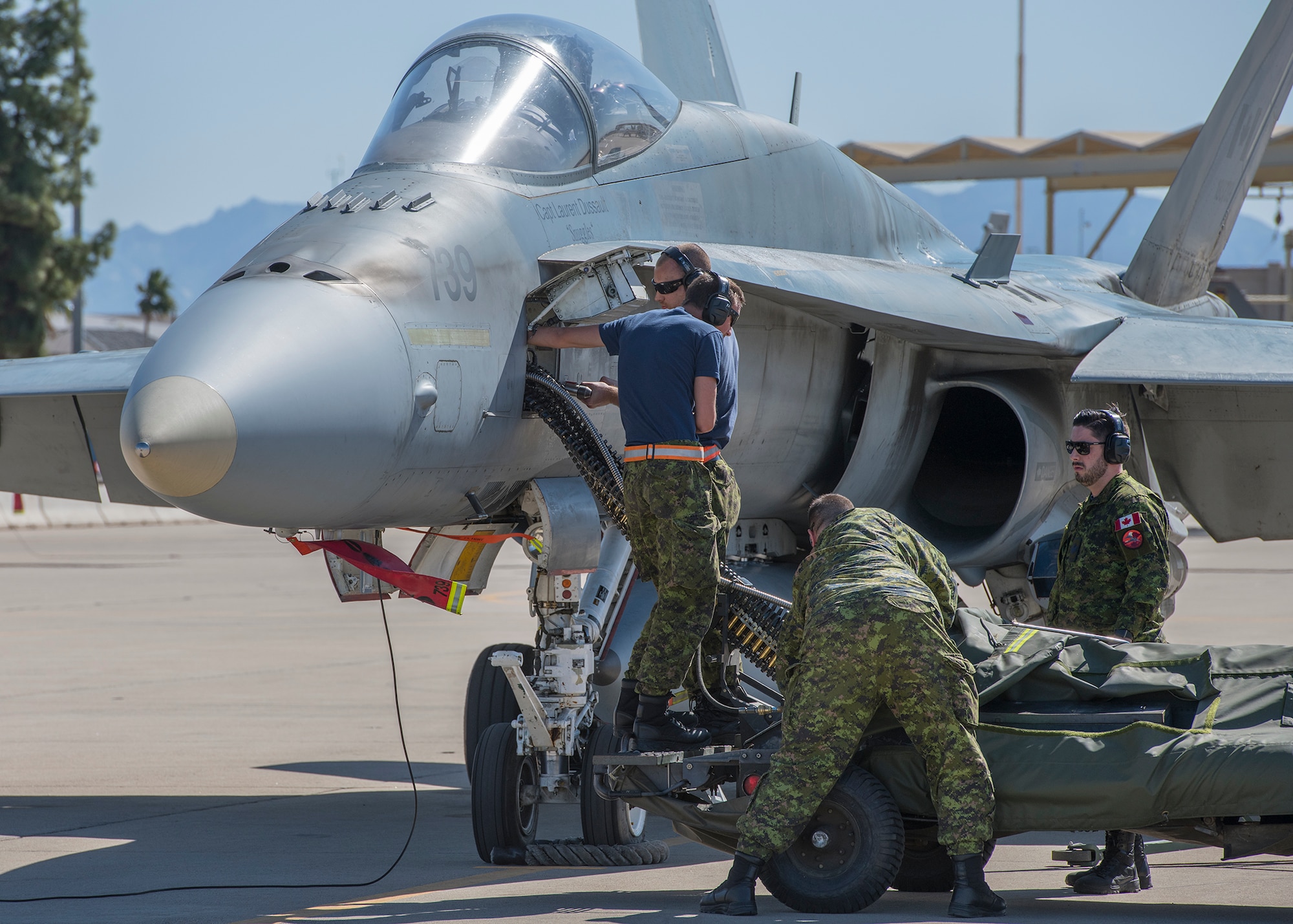 Royal Canadian air force maintainers, assigned to the 433rd Tactical Fighter Squadron in Canadian Forces Base Bagotville, Quebec, Canada, load ammunition onto a CF-18 Hornet, Feb. 25, 2020, at Luke Air Force Base, Ariz.
