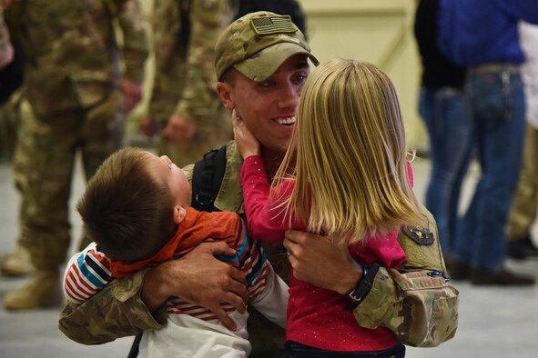 An Airman from the 819th Rapid Engineer Deployable Heavy Operational Repair Squadron Engineers (RED HORSE) hugs his children Nov. 5, 2018, at the airfields located on Malmstrom Air Force Base, Mont.