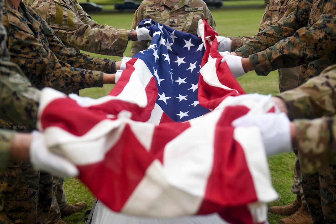 Service members hold an American flag during a disinterment ceremony.