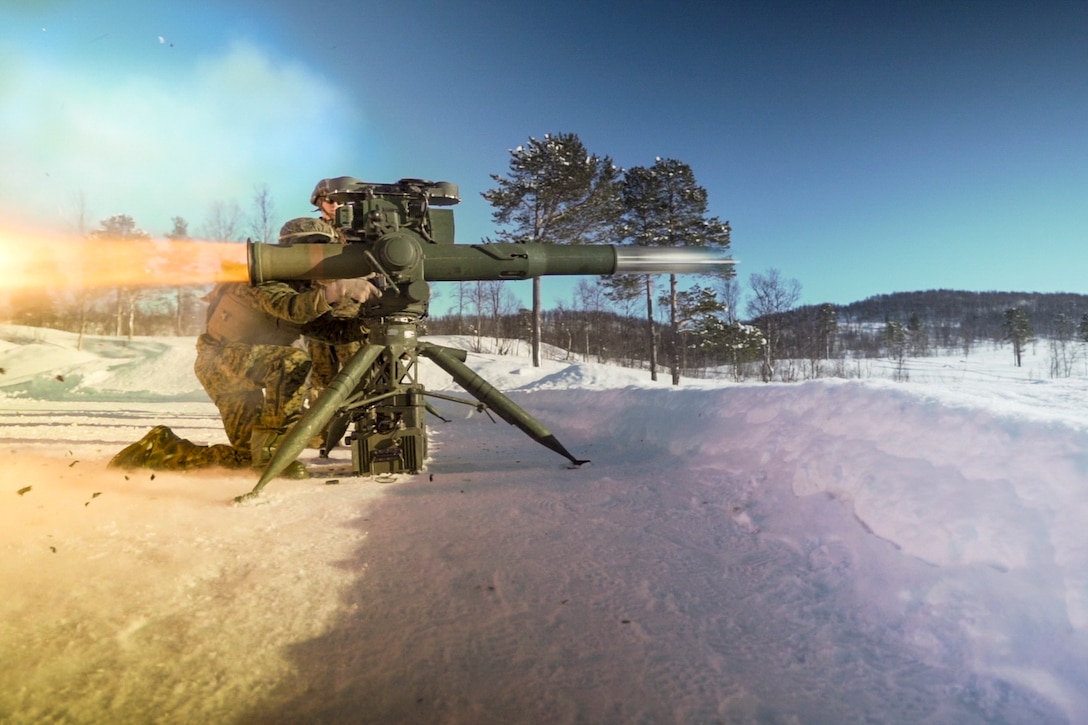 Two Marines fire a missile system in snow.