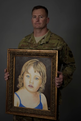 A man holds a painting of his daughter.