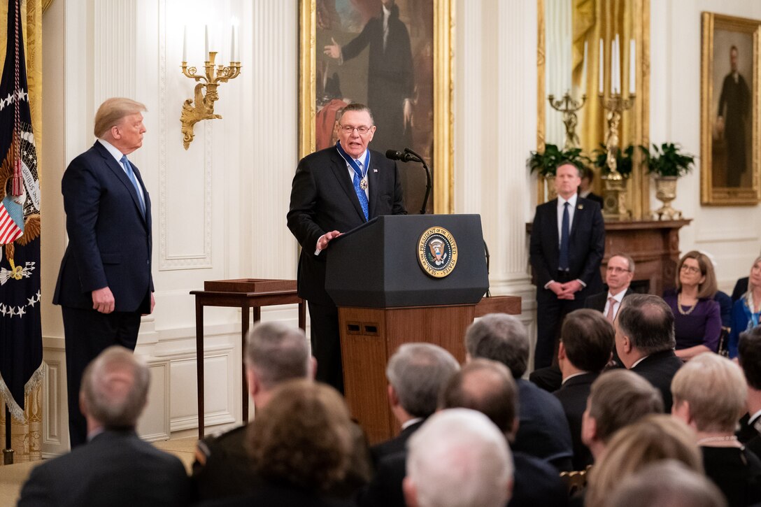 Two men stand on a stage at a ceremony.