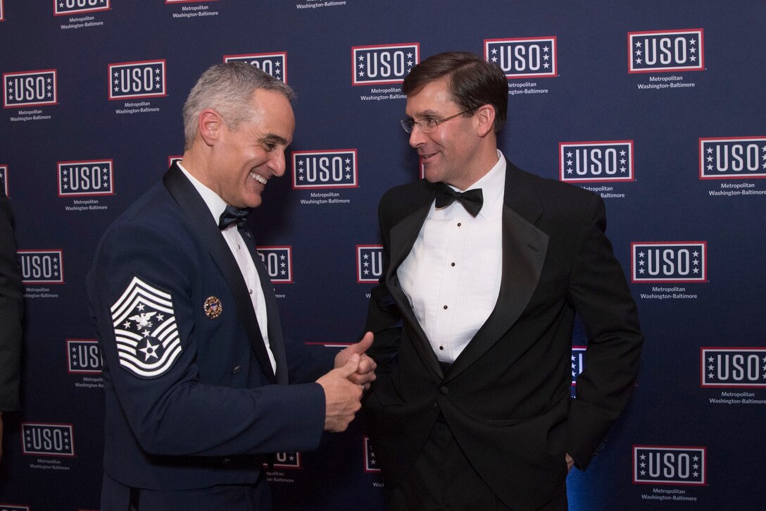 Defense Secretary Dr. Mark T. Esper talks with Senior Enlisted Advisor to the Chairman Ramon “CZ” Colon-Lopez in front of USO signage.