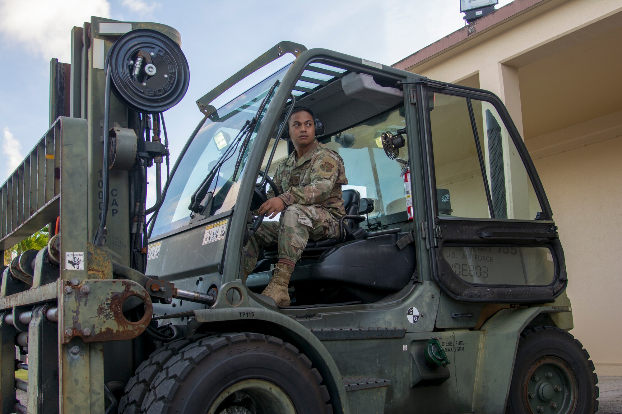 Picture of U.S. Air Force Staff Sgt. Jomar Cruz, 44th Aerial Port Squadron transportation specialist, observing his spotter as he operates a forklift during the first Patriot Express mission at Andersen Air Force Base, March 7, 2020.