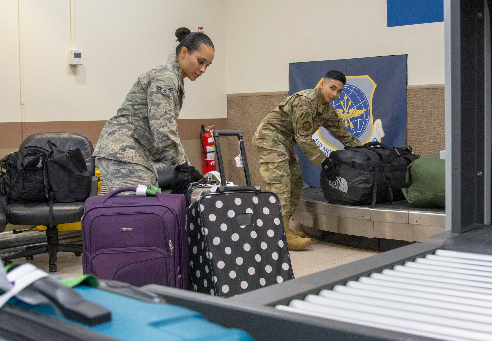 Picture of U.S. Air Force Airman 1st Class Camarin Perez, left, and Senior Airman Joshua San Agustin, 44th Aerial Port Squadron transportation specialists, moving baggage to a conveyor belt for loading onto an aircraft in support of the first Patriot Express mission at Andersen Air Force Base, Guam, March 7, 2020.
