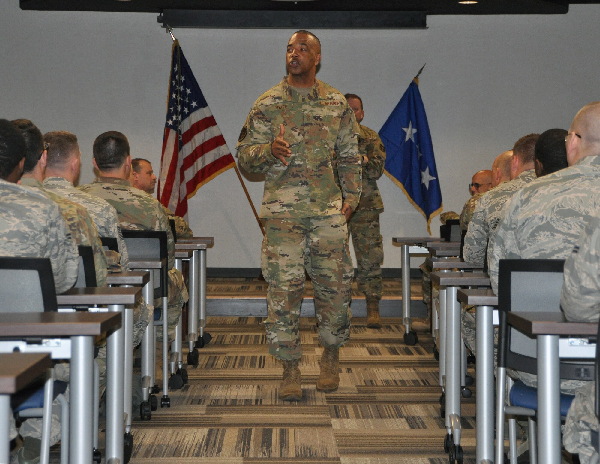 a person stands in front of others in a conference room.