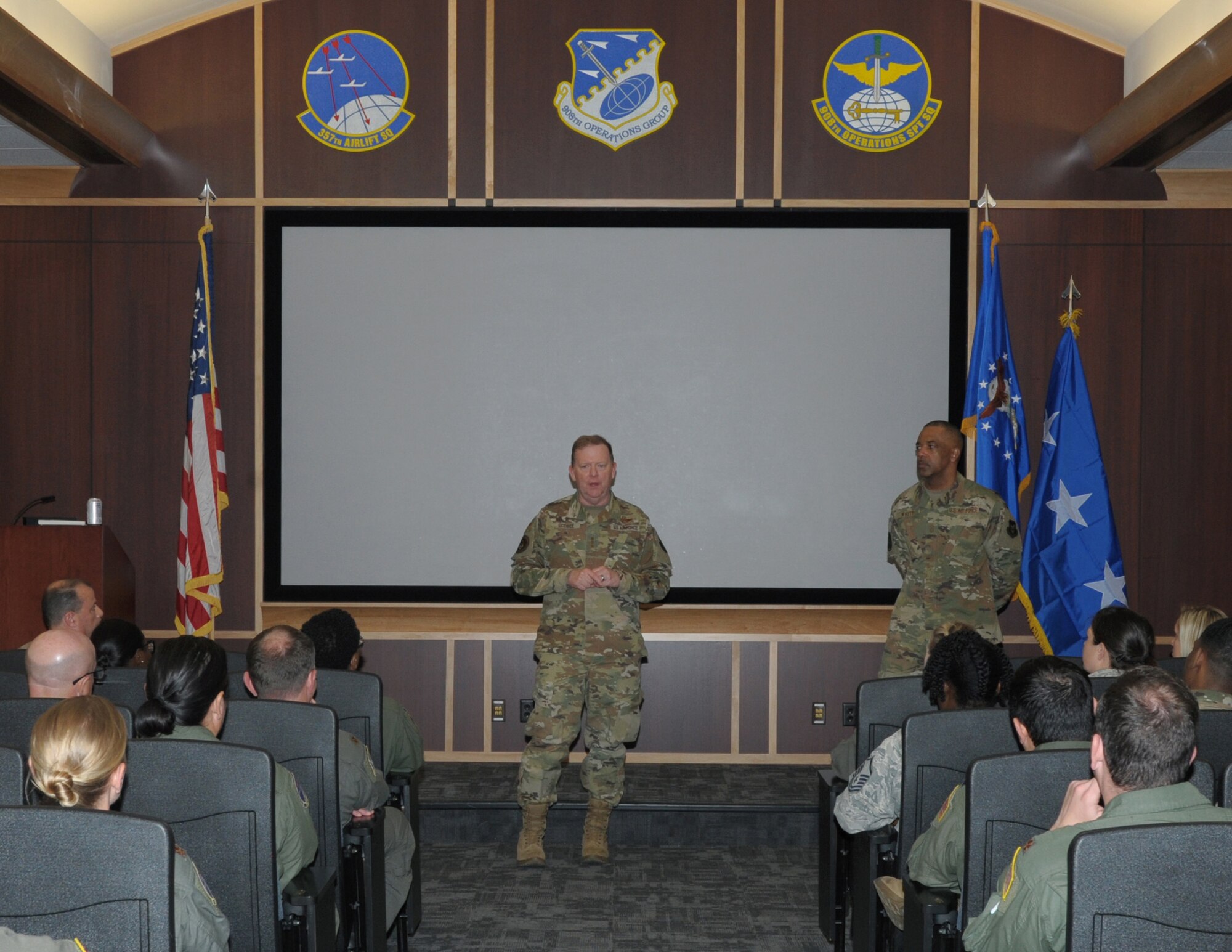 a person stands in front of others in an auditorium.