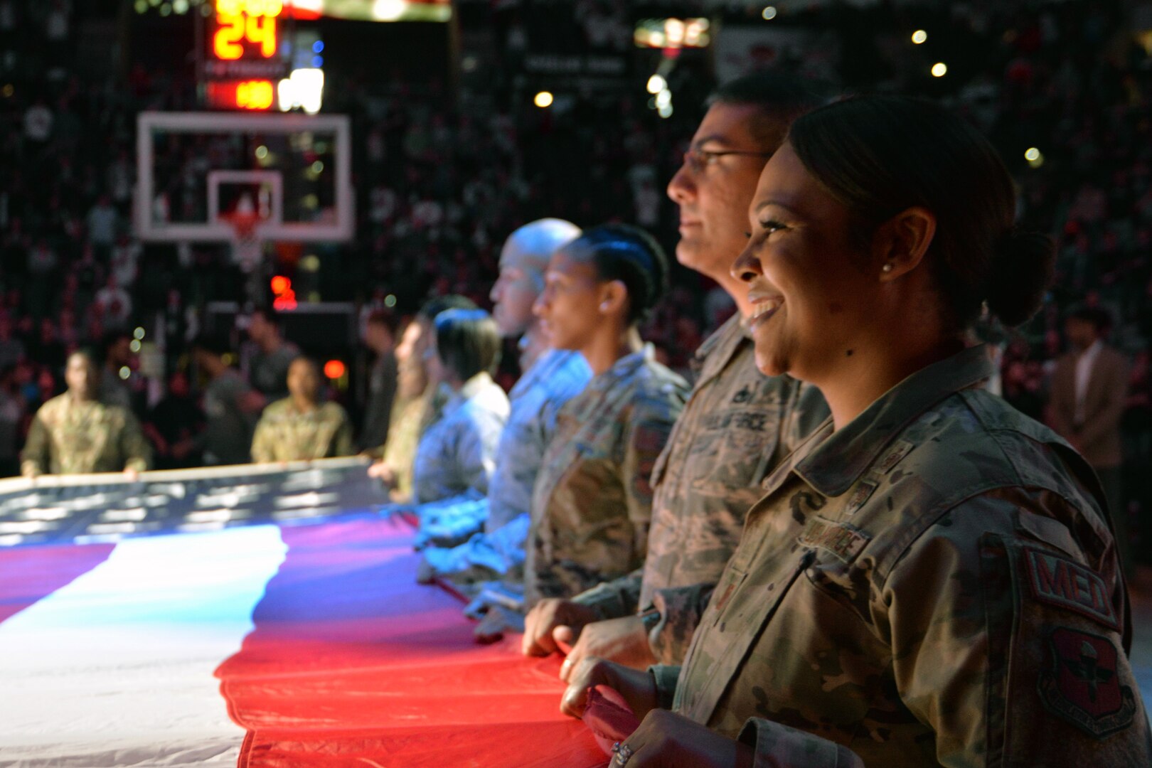 Air Force and Army servicemembers display the American flag while another Airman sings the national anthem at the opening ceremony to a Spurs basketball game March 10, 2020 in San Antonio.