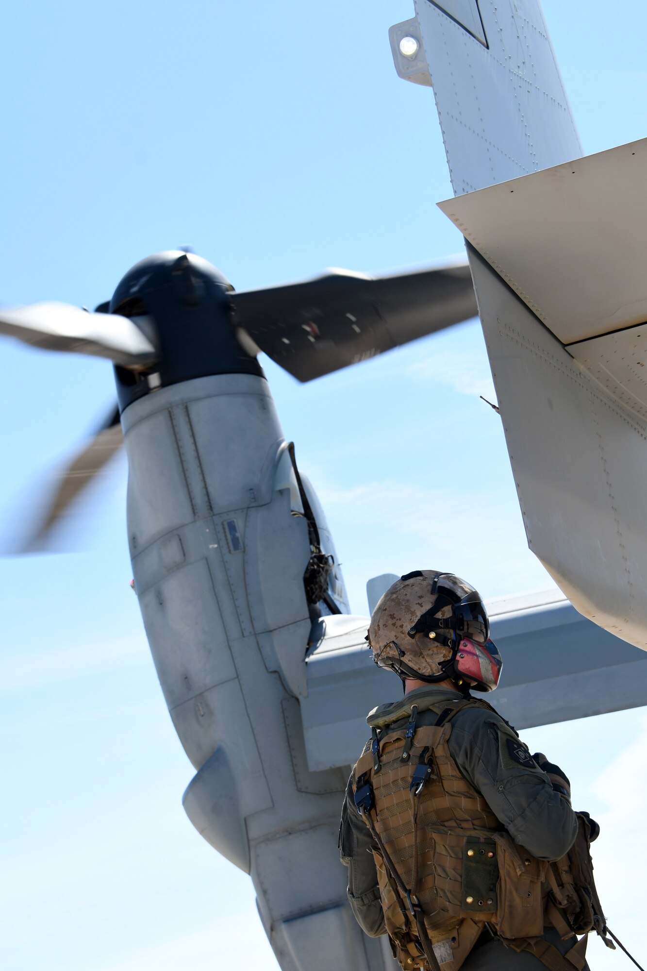 A photo of a Marine standing next to a MV-22B Osprey