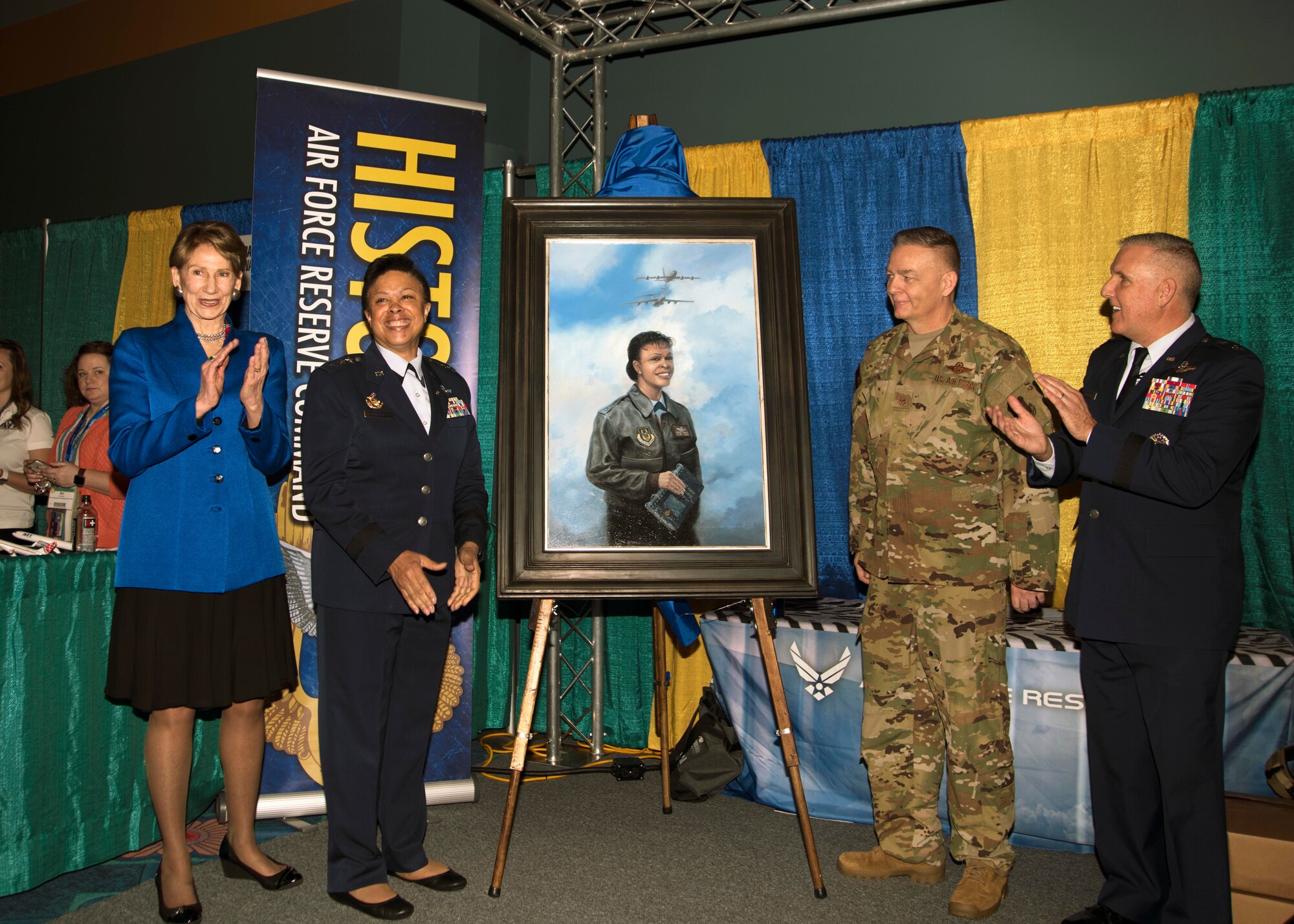 Image of Secretary of the Air Force Barbara Barrett, Lt. Gen. Stayce Harris (retired), Senior Master Sgt. Darby Perrin, heritage and combat artist and  Maj. Gen. John Flournoy, AFRC deputy commander unveiled a painting a portrait of Harris during the 2020 Women in Aviation Conference, March 6 in Orlando, Florida. The portrait shows Harris standing in a flight jacket with flight crew checklists in hand with a KC-135R and C-141-B flying overhead, both aircraft were flown by Harris. (U.S. Air Force photo by Staff. Sgt. Cierra Presentado)
