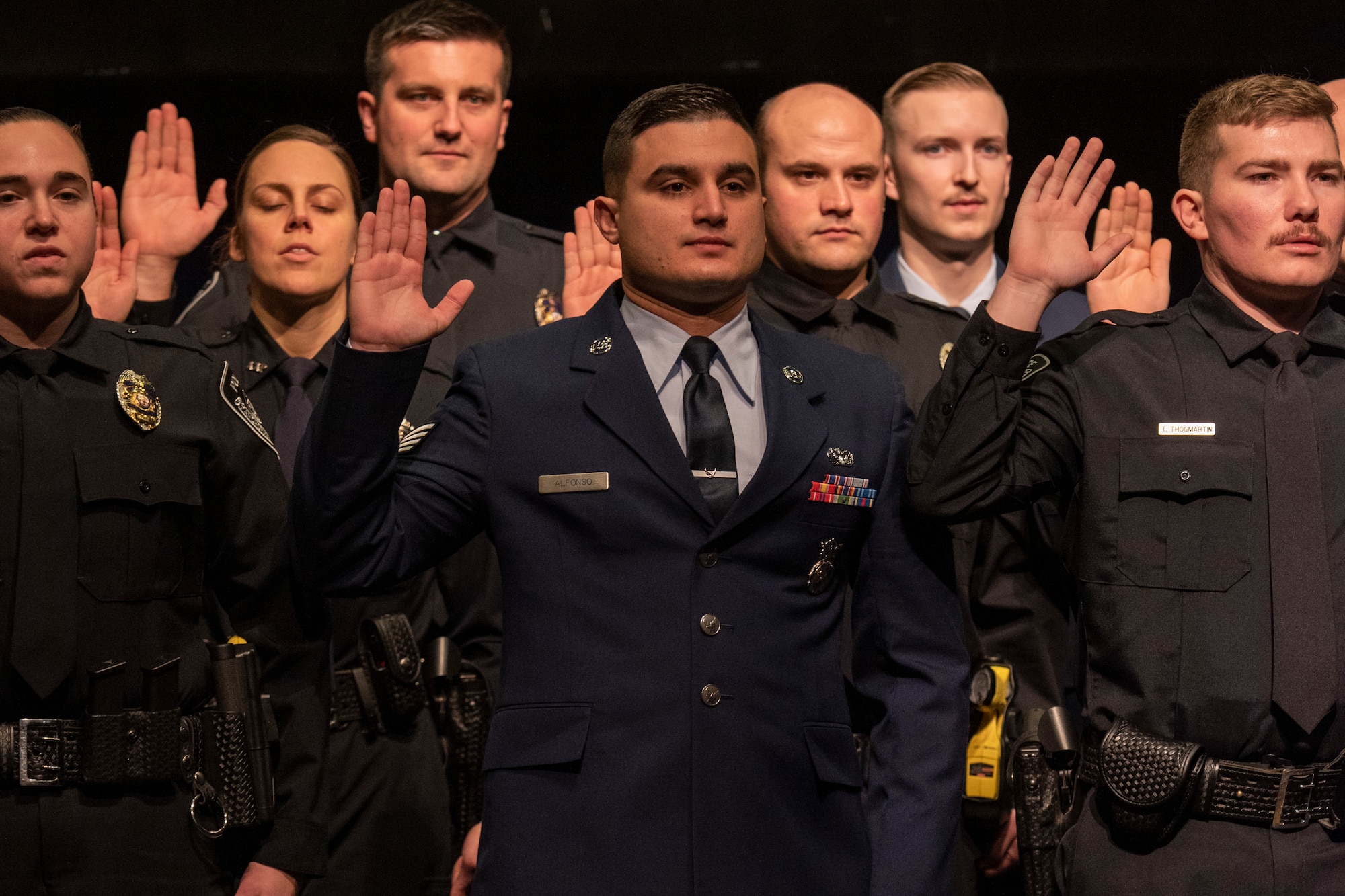 U.S. Air Force Staff Sgt. Ramses Alfonso (center), 673d Security Forces Squadron lead patrolman, swears in at the Anchorage Police Department 19-1 Academy graduation in Anchorage, Alaska, Dec. 5, 2019. Alfonso earned the Distinguished Honor Graduate Award, Class Valedictorian, Top Shooter, and Top Defensive Driver in the Emergency Vehicle Operations Course. The partnership between the squadron and the Anchorage Police Department provides Airmen with a clearer understanding of municipal police procedures as well as builds contacts with all partner law enforcement agencies who participate in the academy.