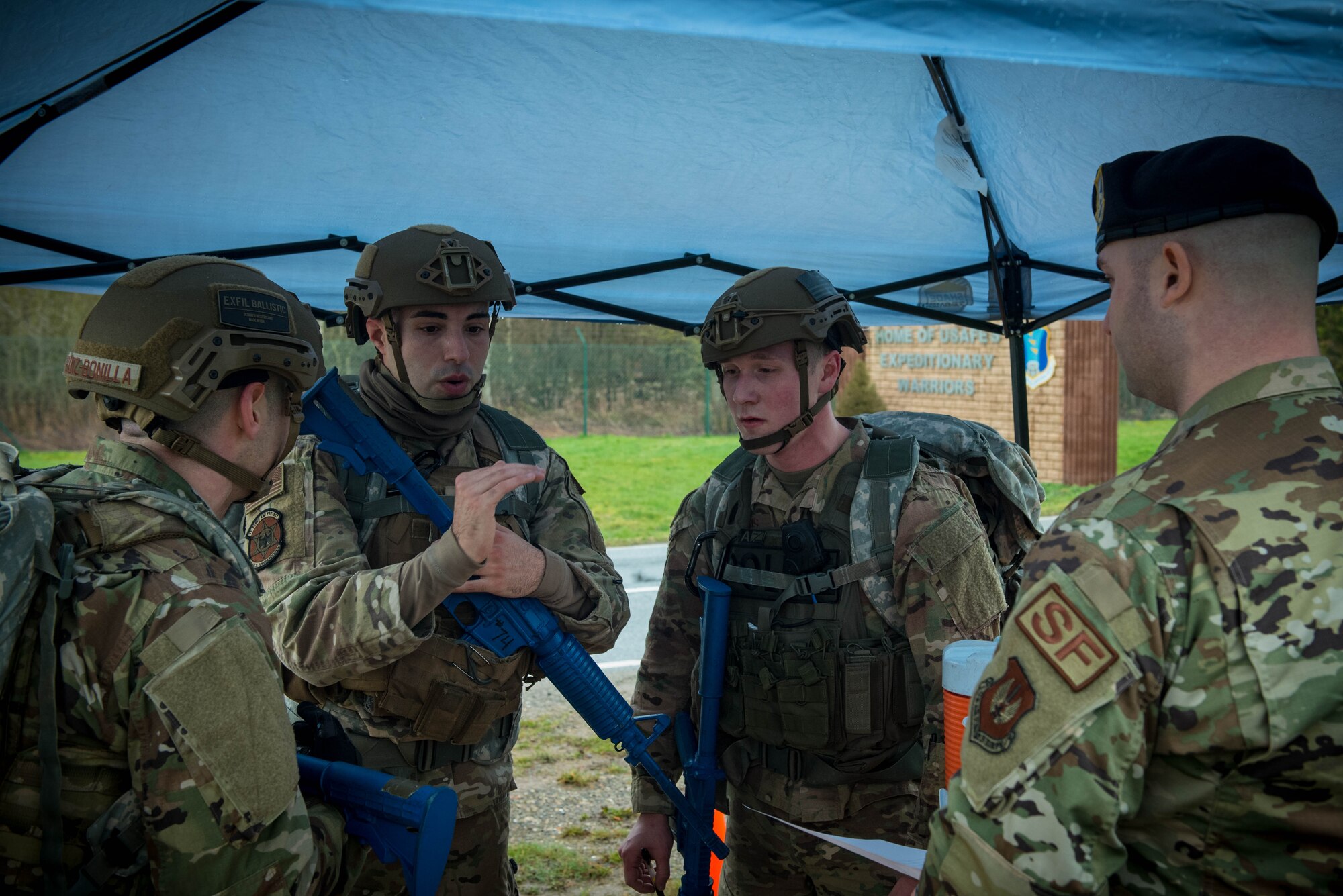 U.S. Air Force security forces members discuss the SALUTE reporting procedures under a tent.