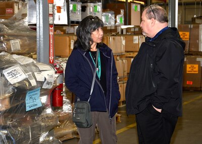 Two people have a discussion in a warehouse