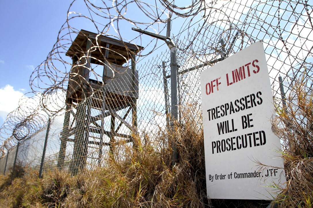 An "Off Limits" sign hangs on a fence that is topped with concertina wire.