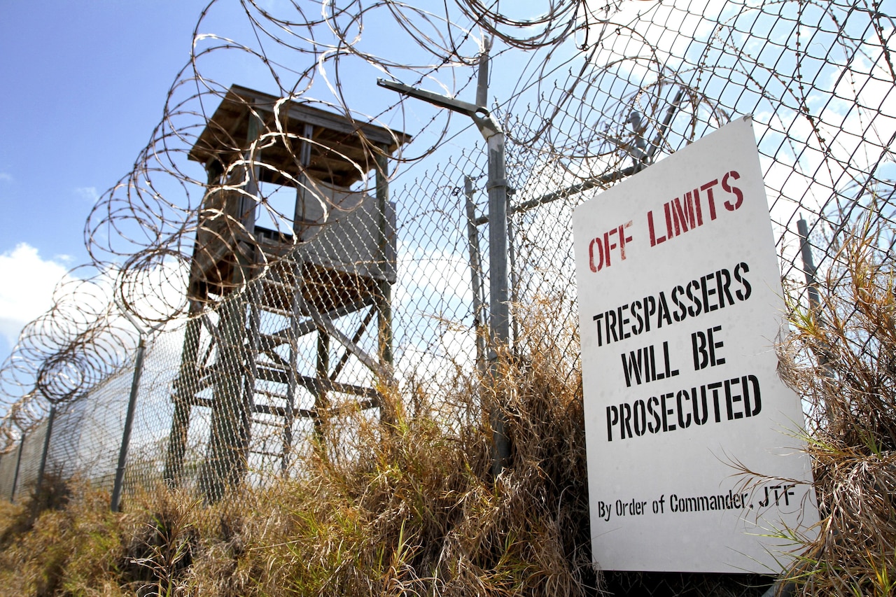 An "Off Limits" sign hangs on a fence that is topped with concertina wire.