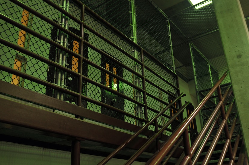 A metal staircase ascends to a caged area with detention facility cells.