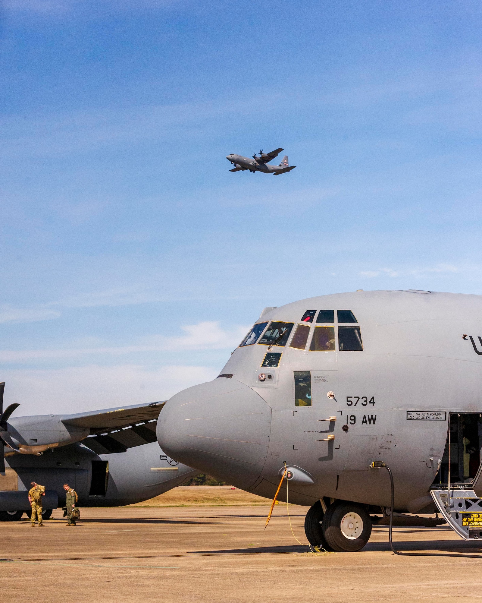 AC-130J Hercules aircraft takes off. with two aircraft in foreground.