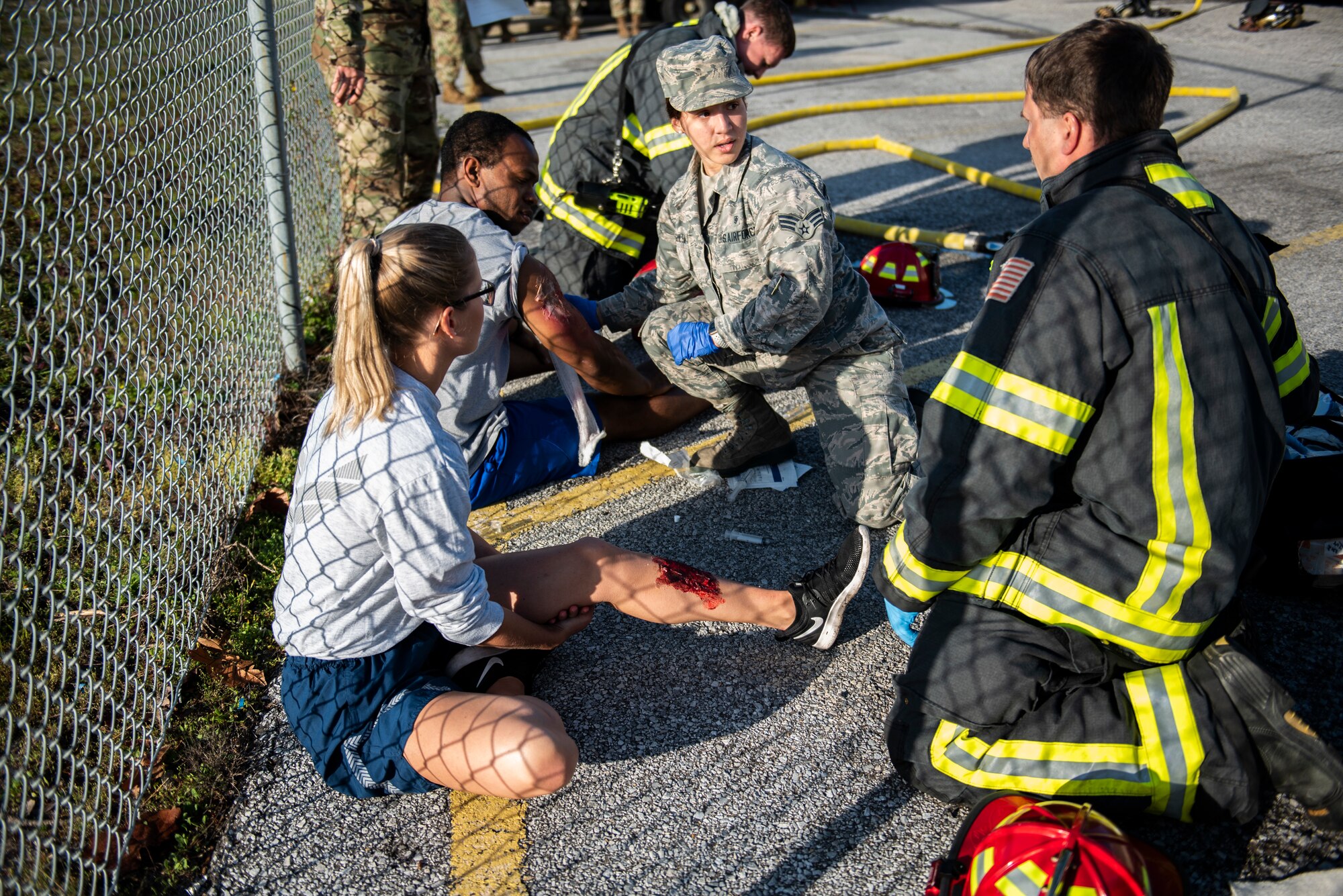 Tech. Sgt. Haley Lecomte, 325th Medical Group executive assistant, left, and Staff Sgt. Zachary Collins, 325th Operational Medical Readiness Squadron Ambulance Services Department technician, pretend to be medical trauma patients during an exercise at Tyndall Air Force Base, Florida, March 12, 2020. Senior Airman Ashley Deliz Aguilera, 325th OMRS ASD technician, center, and Staff Sgt. Jeffery Wells, 325th Civil Engineer Squadron fire department emergency medical technician, right, administered on scene medical treatment prior to patient transfer. (U.S. Air Force photo by Staff Sgt. Magen M. Reeves)