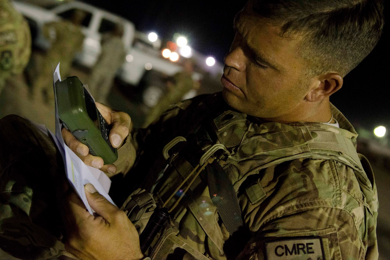 A soldier uses a handheld GPS device.