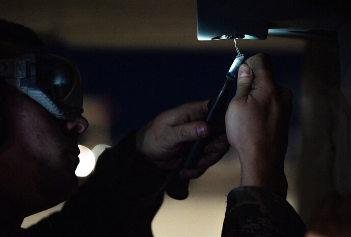 Airman tightens a wire on a jet.