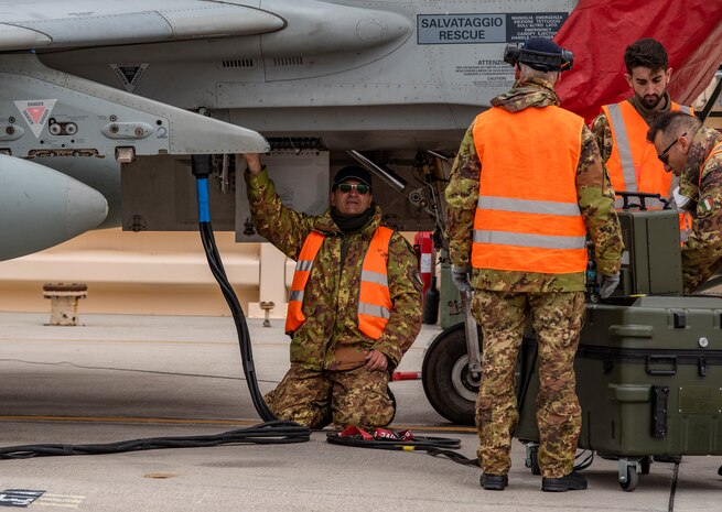 Airman attaches pump to a jet.