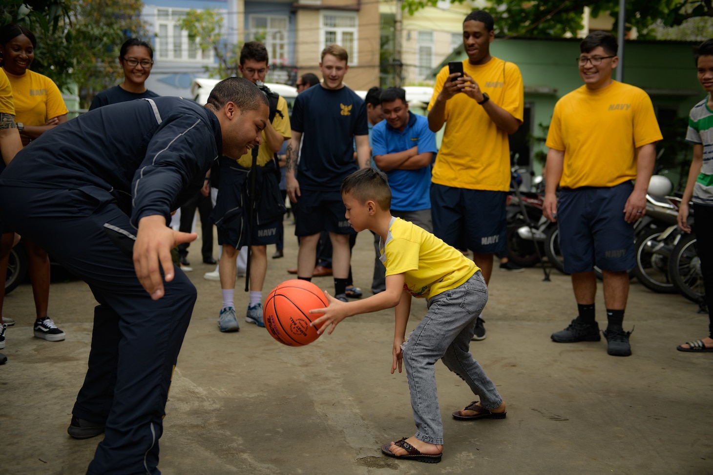 200306-N-YQ383-1567 VIETNAM (March 6, 2020) U.S. Navy Aviation Ordnanceman 3rd Class Khaden D. Vaughn, from Columbus, Ohio, plays basketball with a child at the Dorothea’s Project Legacies Charity Center, Da Nang, Vietnam, during a community relations project organized by the aircraft carrier USS Theodore Roosevelt (CVN 71) March 6, 2020. Theodore Roosevelt and the Ticonderoga-class guided-missile cruiser USS Bunker Hill (CG 52) are in Vietnam for a port visit during their scheduled deployment to the Indo-Pacific.