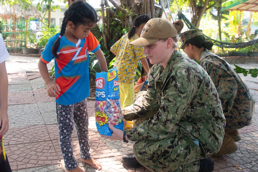 A sailor offers candy to a girl.