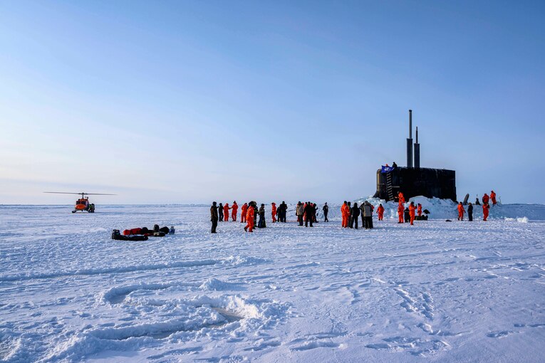 A group of U.S. service members walk in snow.