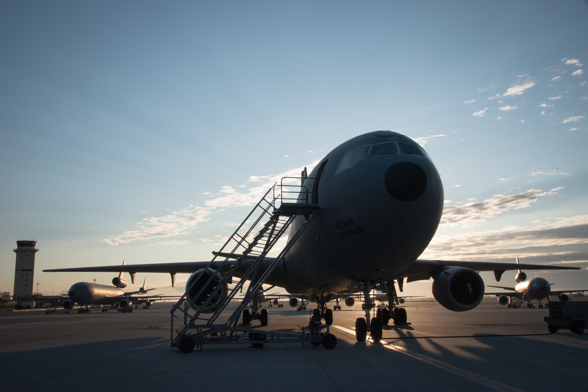 The sun rises behind a KC-10 Extender on the flight line