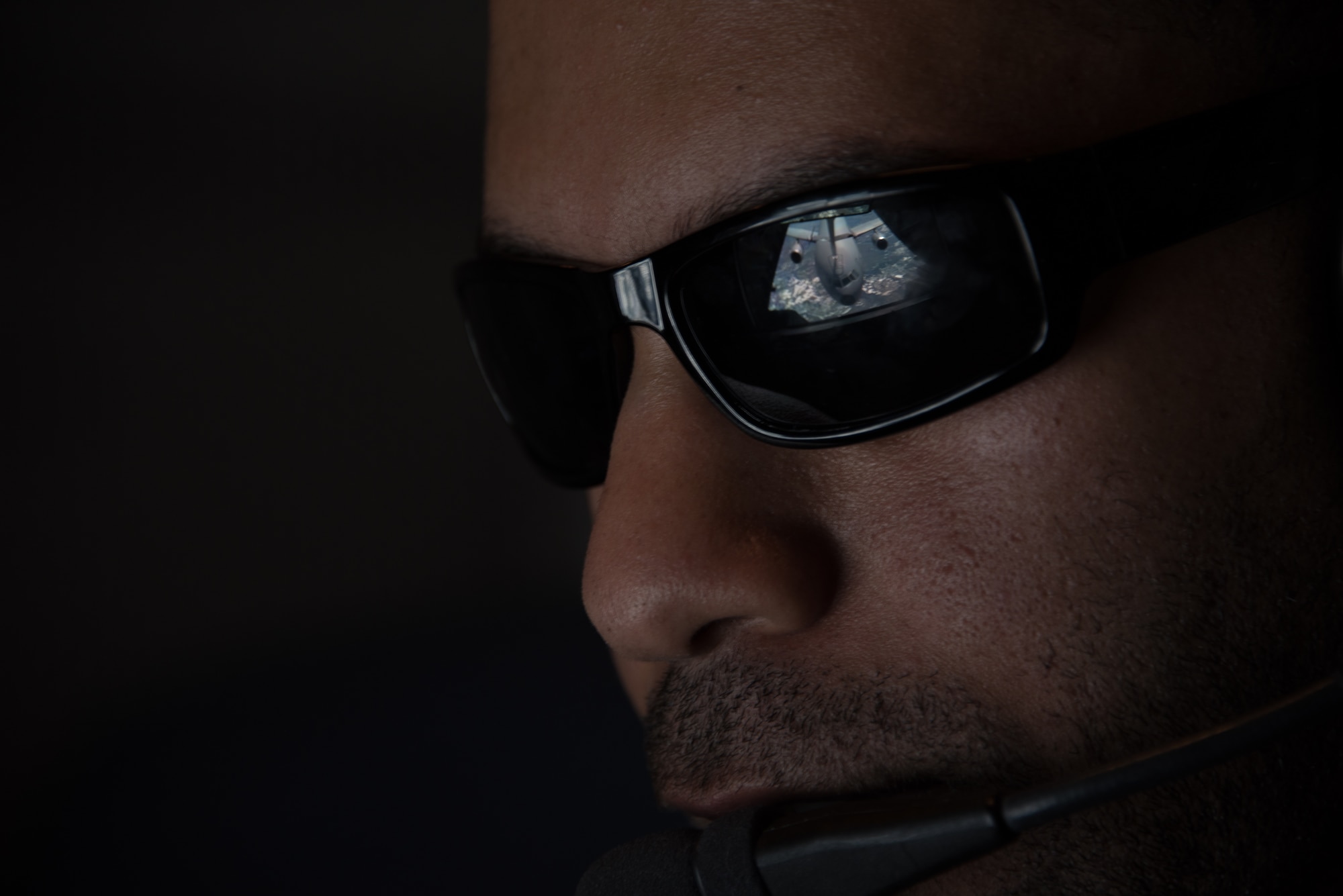 Sunglasses worn by a boom operator show the reflection of a KC-10 boom connecting with another KC-10 Extender