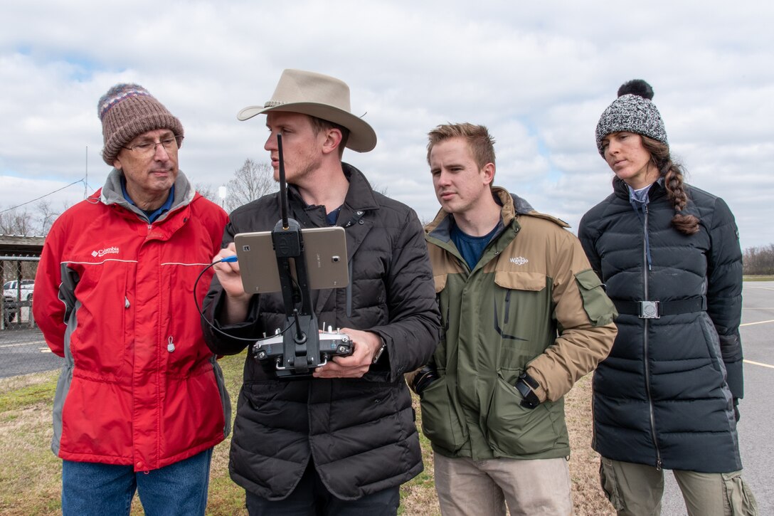 Demonstrator Ross Kenney, second from left, in control of an MD4-1000 Microdrone platform, talks about the system's features with Huntsville Center employees William Noel (left), Benton Williams, and Bethanie Thomas, during a capabilities review for three unmanned aircraft systems Feb. 27 at the Rocket City Radio Controllers complex in southeast Huntsville, Alabama.