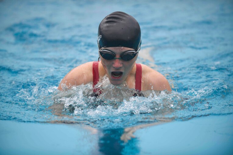 A Marine swims in a pool.