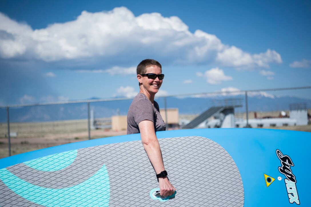 Juli Yim, 50th Force Support Squadron director of outdoor recreation, holds a stand-up paddleboard purchased for outdoor recreation at Schriever Air Force Base, Colorado, May 14, 2019. Along with paddleboards, outdoor recreation also rents campers to Airmen. (U.S. Air Force photo by Airman 1st Class Jonathan Whitely)