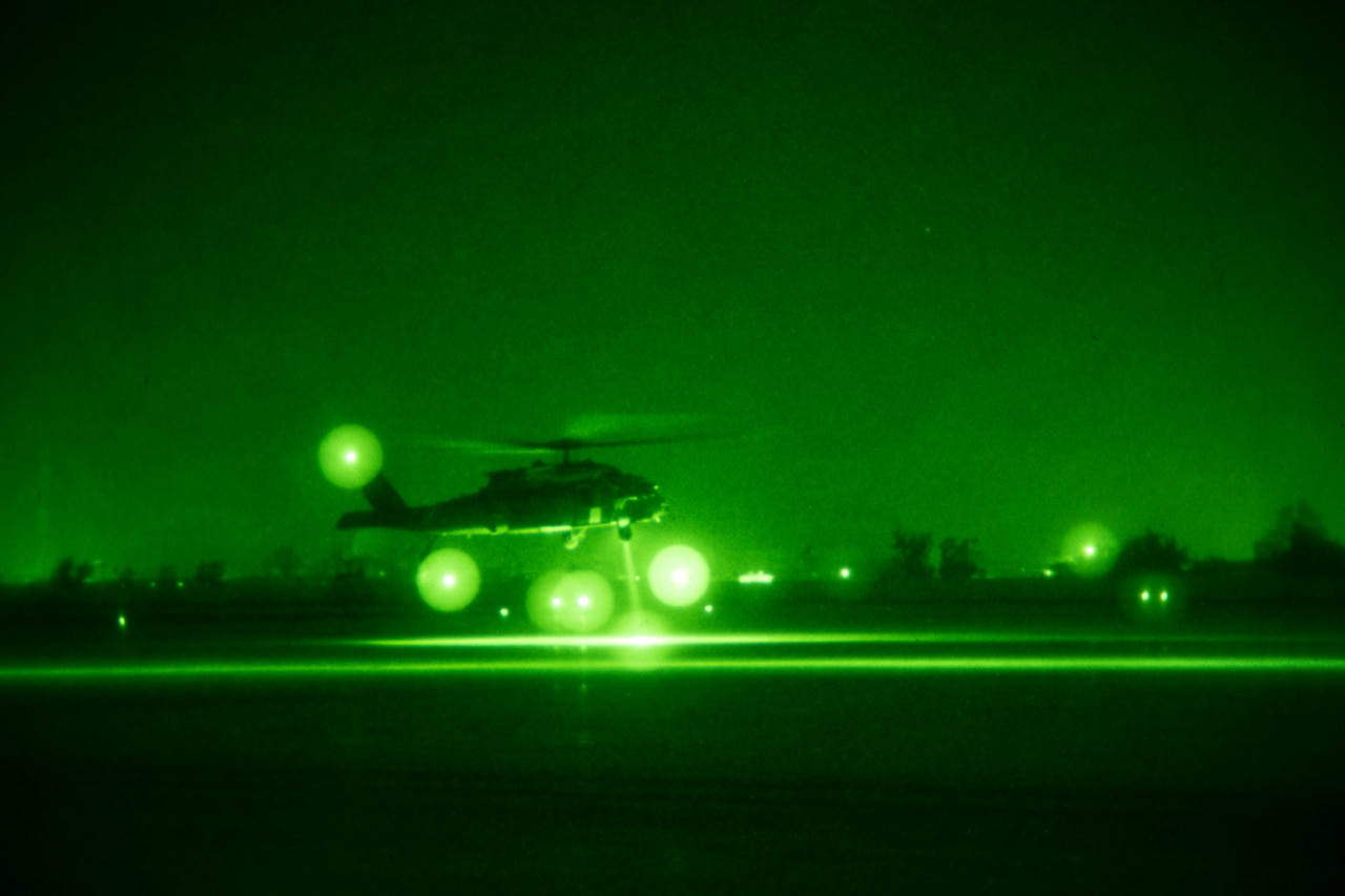 As seen through night vision, a helicopter lands.