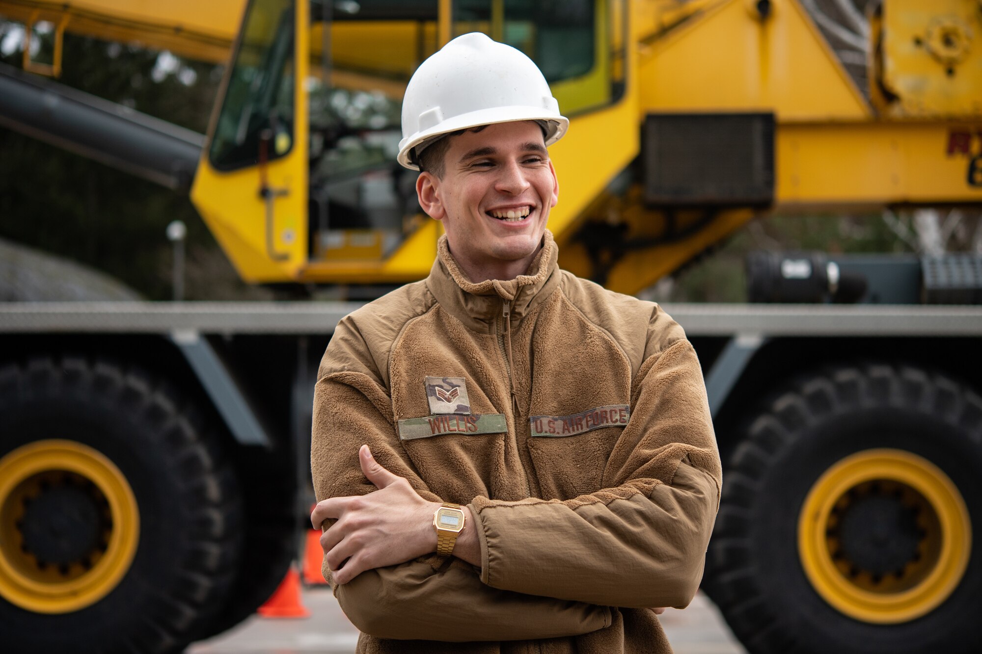 Airman wearing hard-hat standing in front of a crane