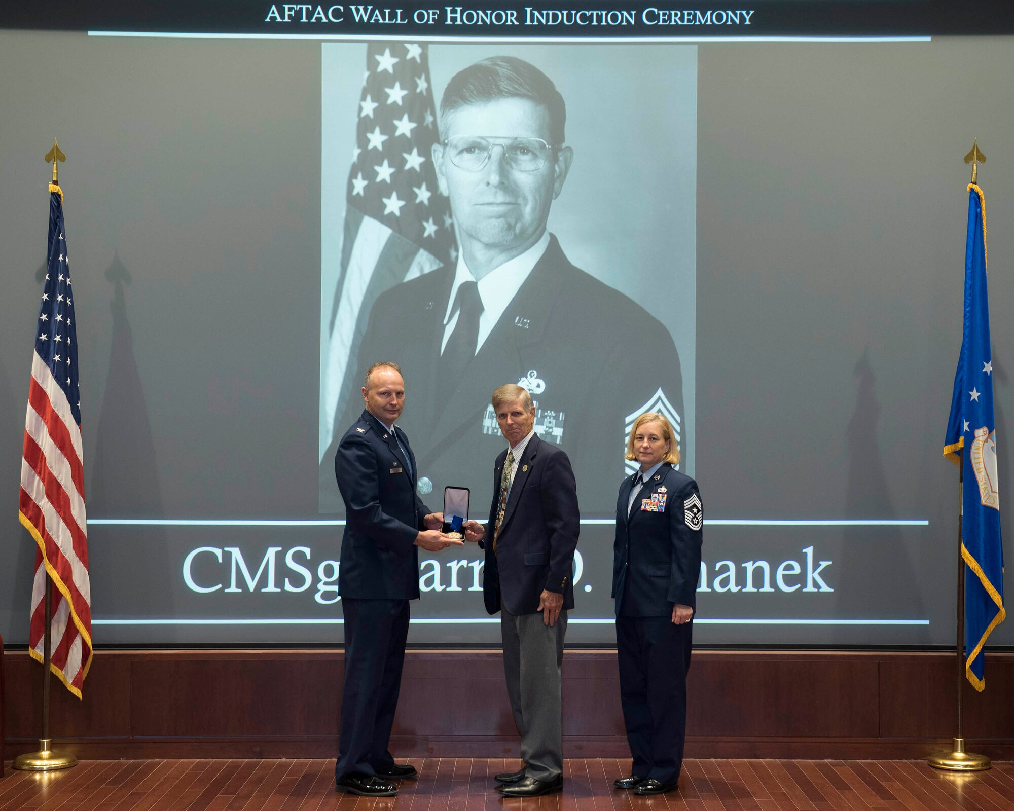 Col. Chad Hartman (left) presents a medallion to retired Chief Master Sgt. Larry Silhanek at a ceremony hosted by the Air Force Technical Applications Center March 11, 2020 at Patrick AFB, Fla.  Silhanek, who was inducted into AFTAC's Wall of Honor, spent 30 year on active duty involved in the center's long range detection mission.  Also pictured is Chief Master Sgt. Amy Long, AFTAC's command chief.  (U.S. Air Force photo by Matthew S. Jurgens)