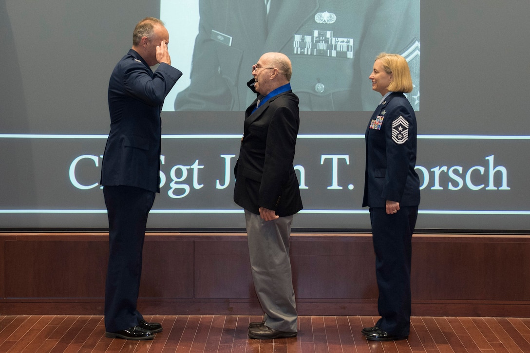 Retired Chief Master Sgt. John T. Horsch (center), renders a salute to Col. Chad Hartman, commander of the Air Force Technical Applications Center, Patrick AFB, Fla., after Hartman presented Horsch with a medallion inducting him into AFTAC's Wall of Honor March 11, 2020.  Also pictured is Chief Master Sgt. Amy Long, AFTAC's command chief.  (U.S. Air Force photo by Matthew S. Jurgens)