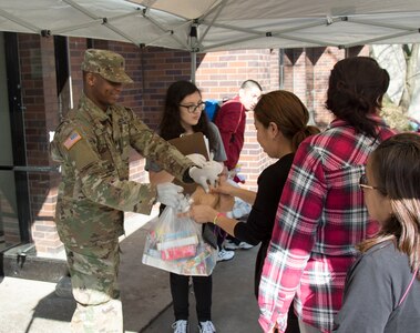 U.S. Army Spc. Rudy Santos, a unit supply specialist assigned to the Headquarters & Headquarters Company, 3rd Battalion, 42nd Combat Aviation Brigade, 42nd Infantry Division, hands out food to members of the community during Operation COVID-19 at the Martin Luther King Community Center, New Rochelle, New York, March 13, 2020. Members of the Army and Air National Guard from numerous states have been activated under Operation COVID-19 to support federal, state and local efforts.