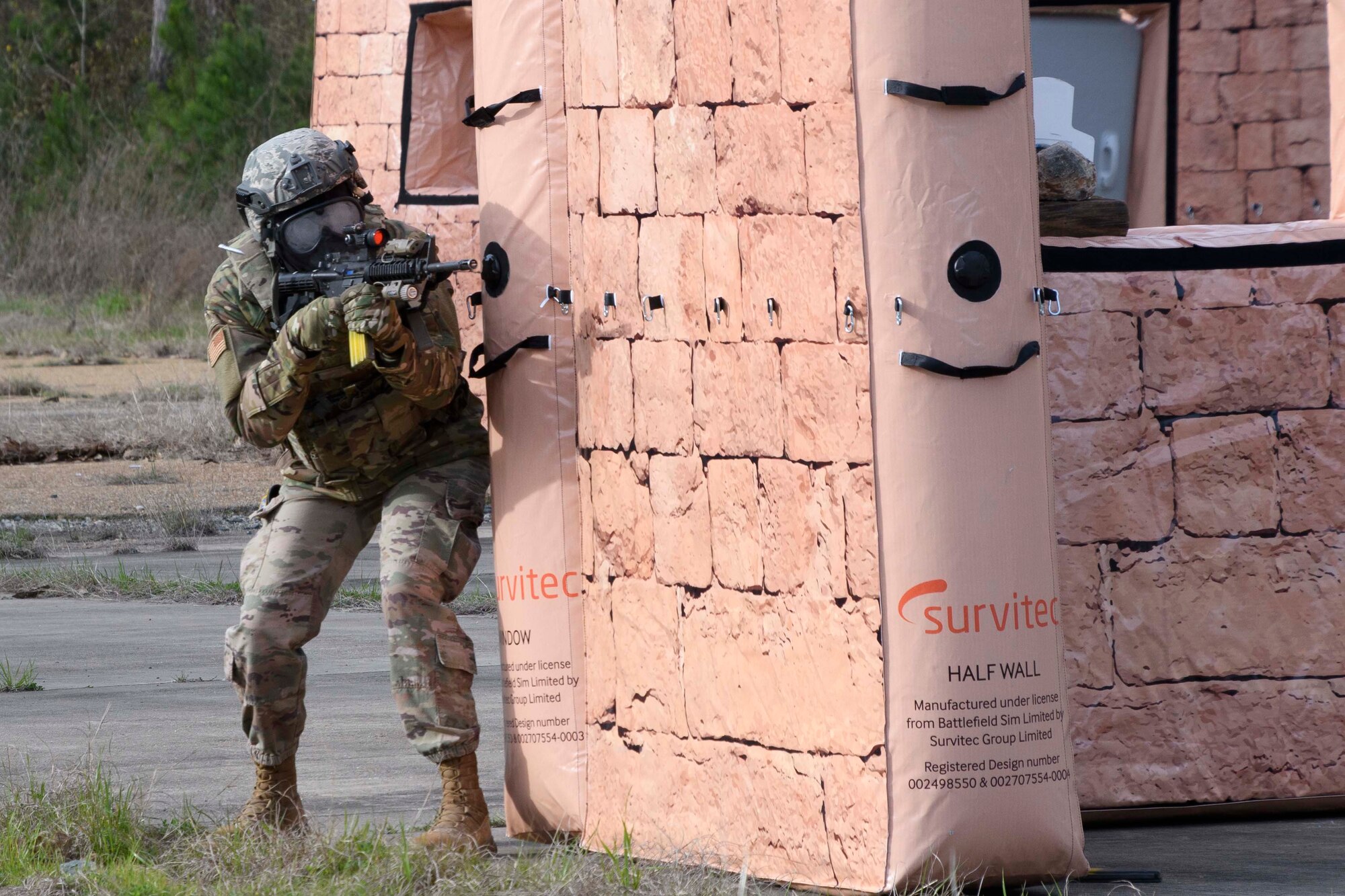 Photo of Airman in combat gear looking around inflatable wall.